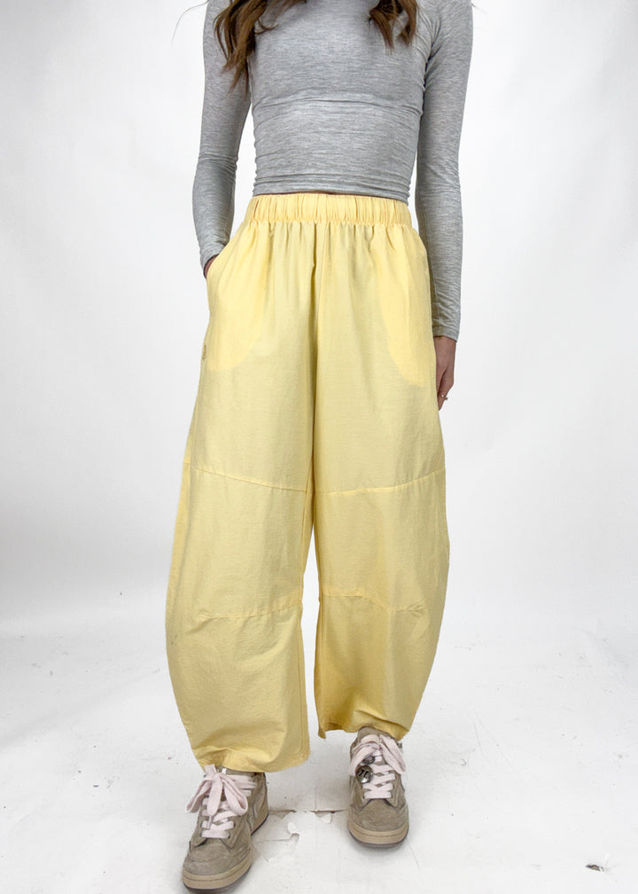 Person wearing yellow wide-leg pants and a gray long-sleeve top on a white background