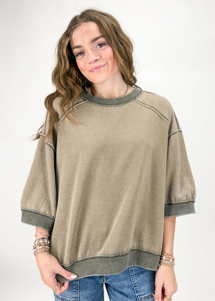 Woman wearing a beige sweater with green accents on a white background