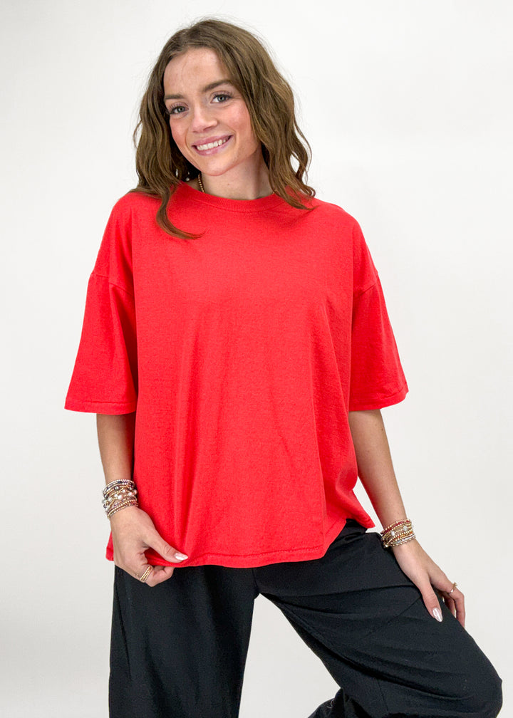 Woman wearing a red oversized t-shirt and black pants on a white background