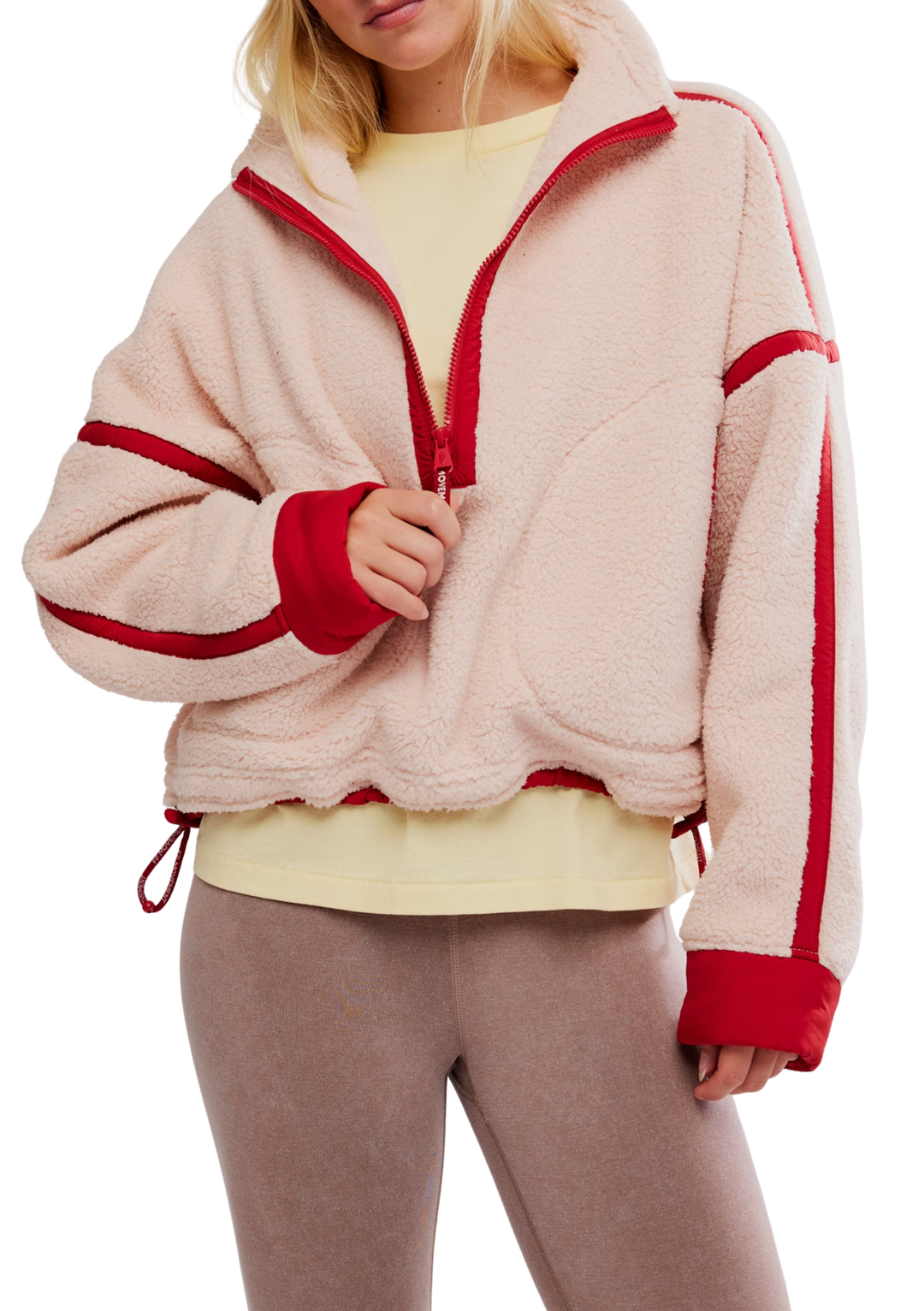 Person wearing a beige fleece jacket with red accents on a white background