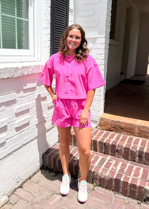 Person wearing a pink outfit standing on steps outside a house.