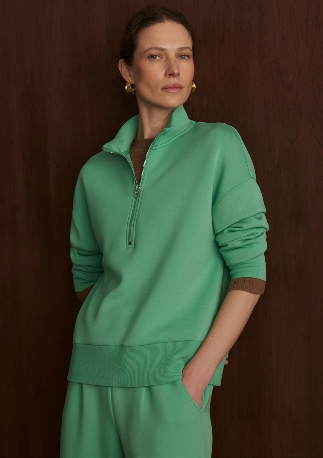 Woman wearing a green tracksuit against a brown background