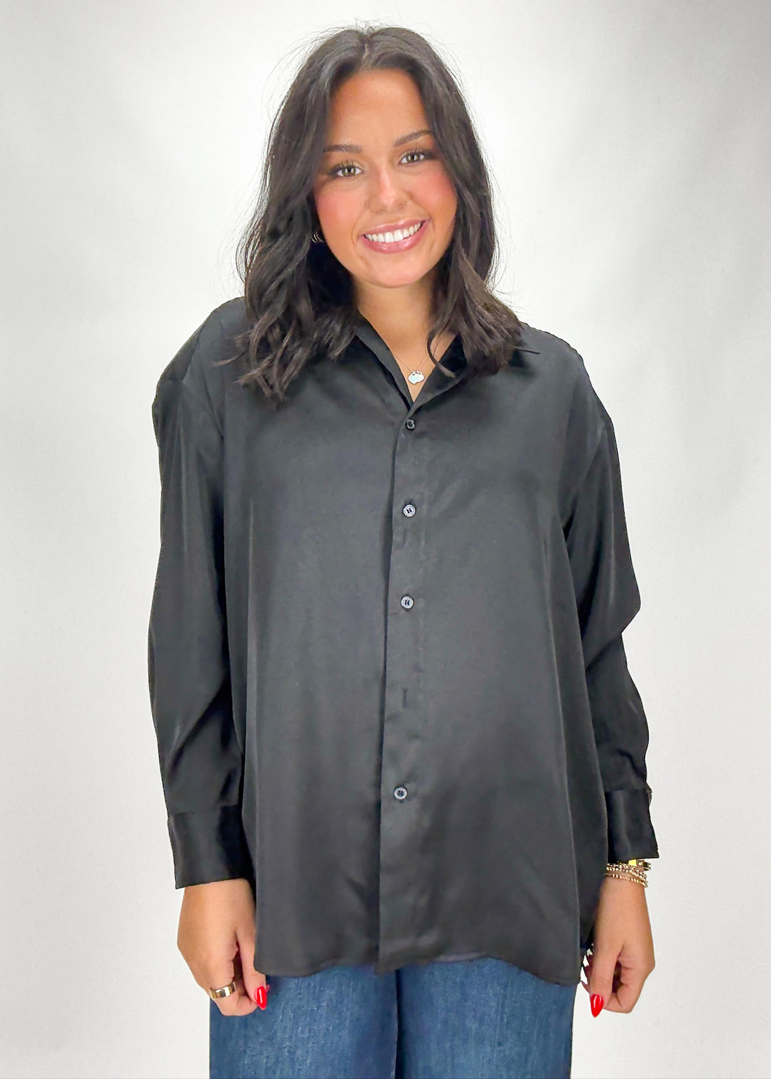 Woman wearing a black button-up shirt and blue jeans on a white background