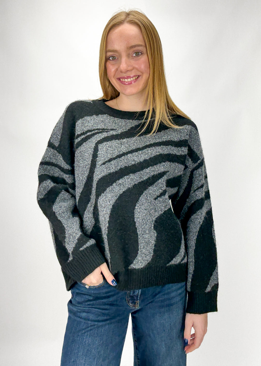 Person wearing a black and gray patterned sweater on a white background