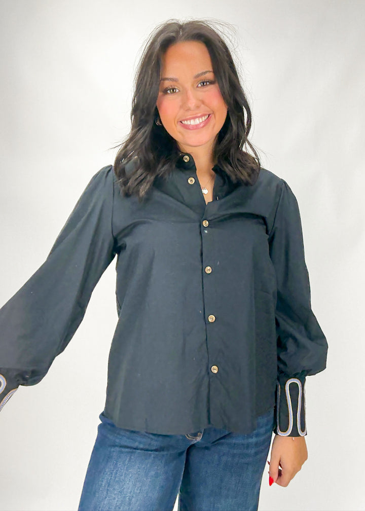 Woman wearing a dark gray button-up shirt with long sleeves on a white background