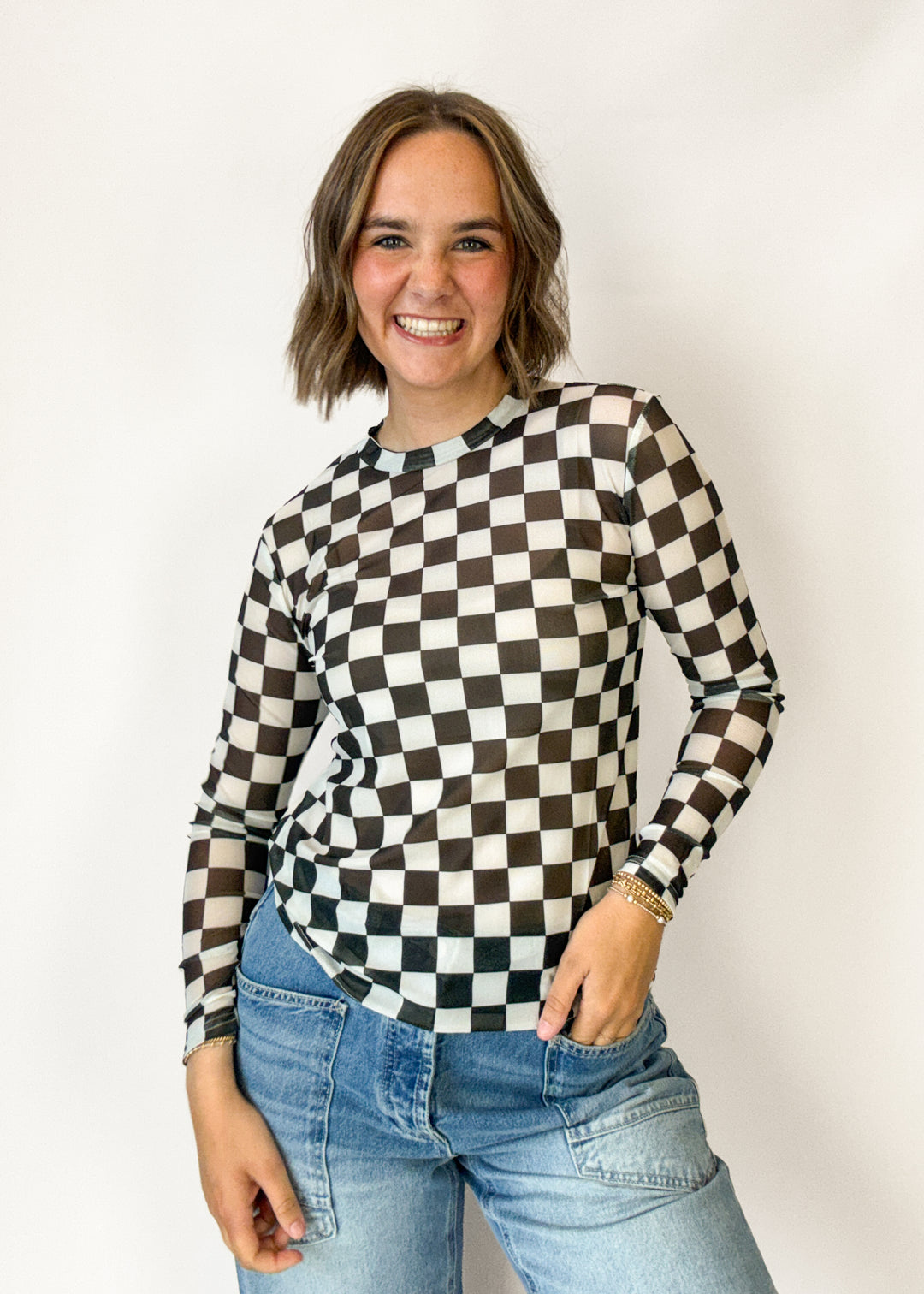 A woman with wearing a black and white checkerboard long-sleeve top 