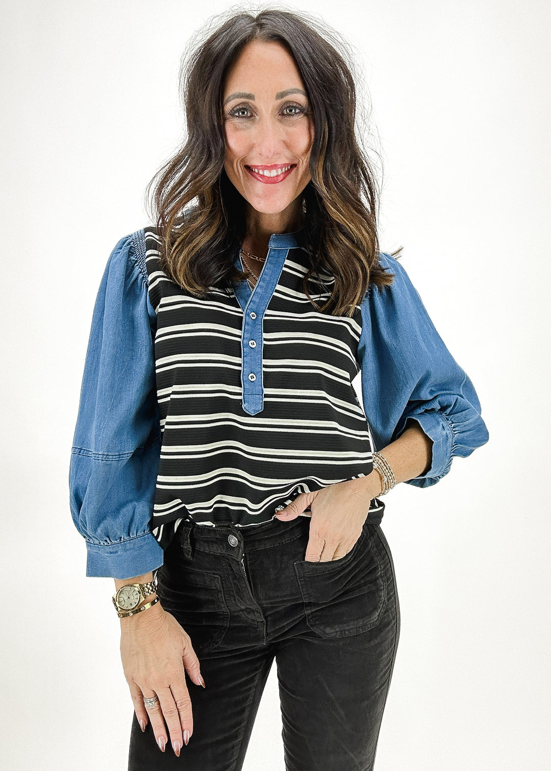 A black and white striped top featuring denim sleeves and button detail on the front, combining casual style with a chic touch.