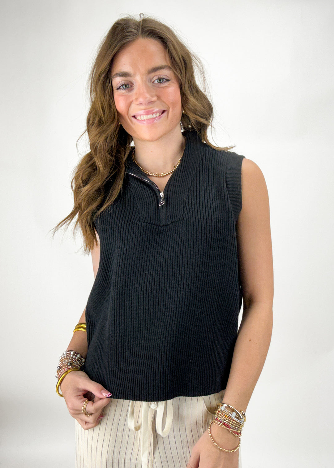 Woman wearing a black sleeveless top with a white background