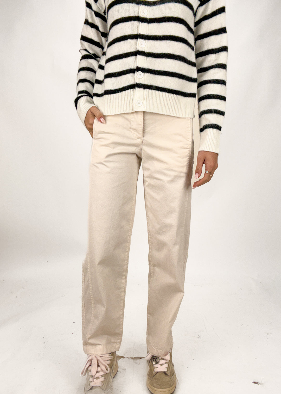 Person wearing a black and white striped sweater and beige pants on a white background