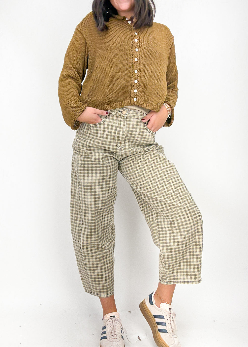 Person wearing a mustard yellow sweater and plaid pants 