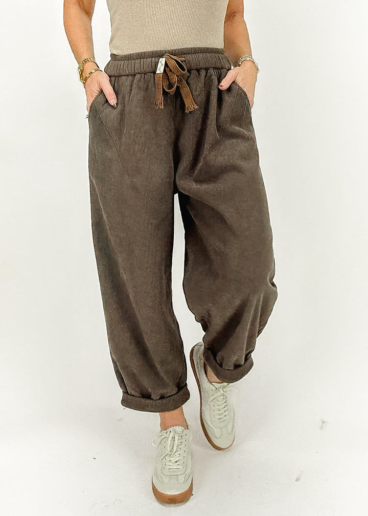 Women's brown corduroy pants featuring a drawstring waist, side pockets, and rolled cuffs for a relaxed and stylish look.