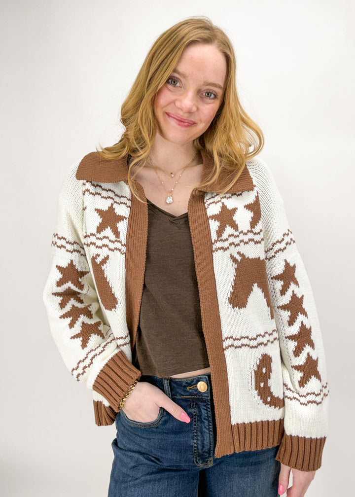 Woman wearing a patterned cardigan with brown and white colors on a plain background