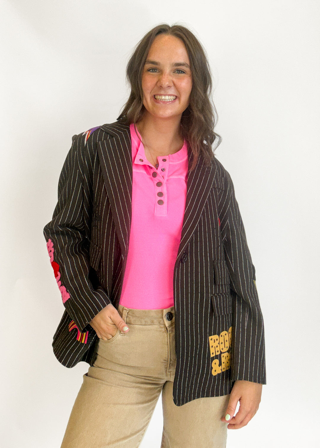 A woman modeling a brown pinstripe blazer with colorful embroidered details on the sleeves and hem