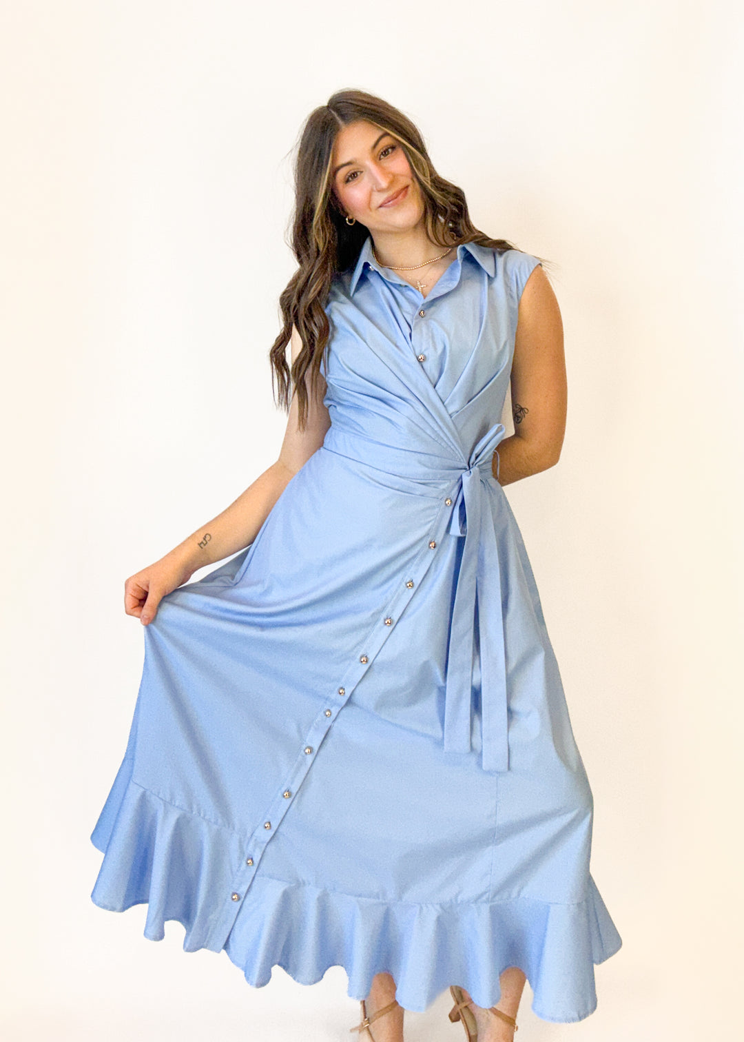 Woman wearing a light blue dress with buttons on a plain background