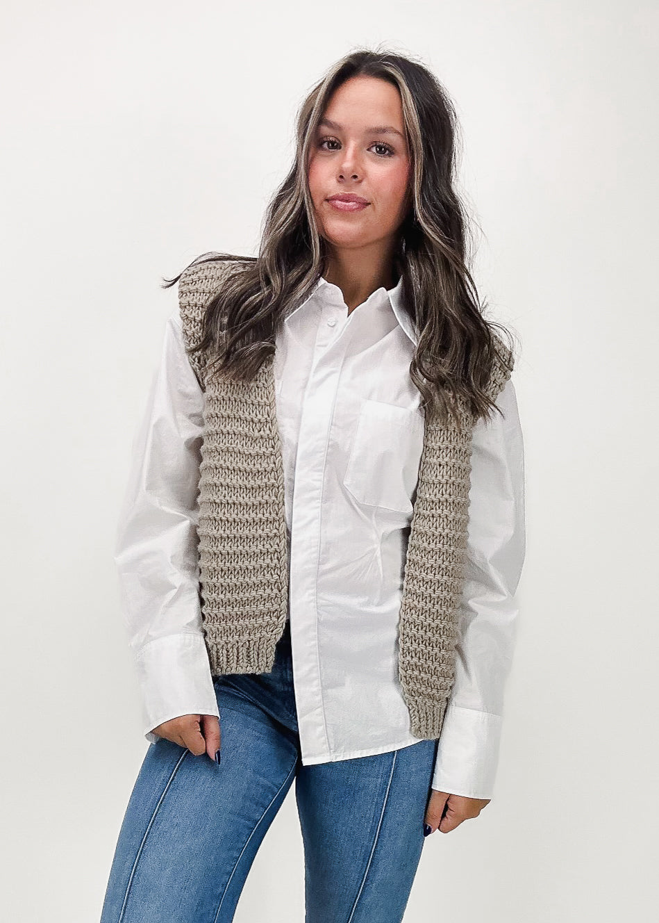 taupe textured knit cardigan vest layered over white poplin button down with medium wash denim jeans