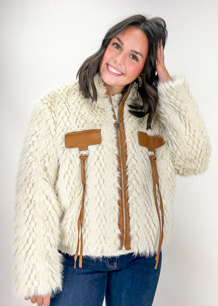 Woman wearing a cream-colored knitted jacket with brown accents