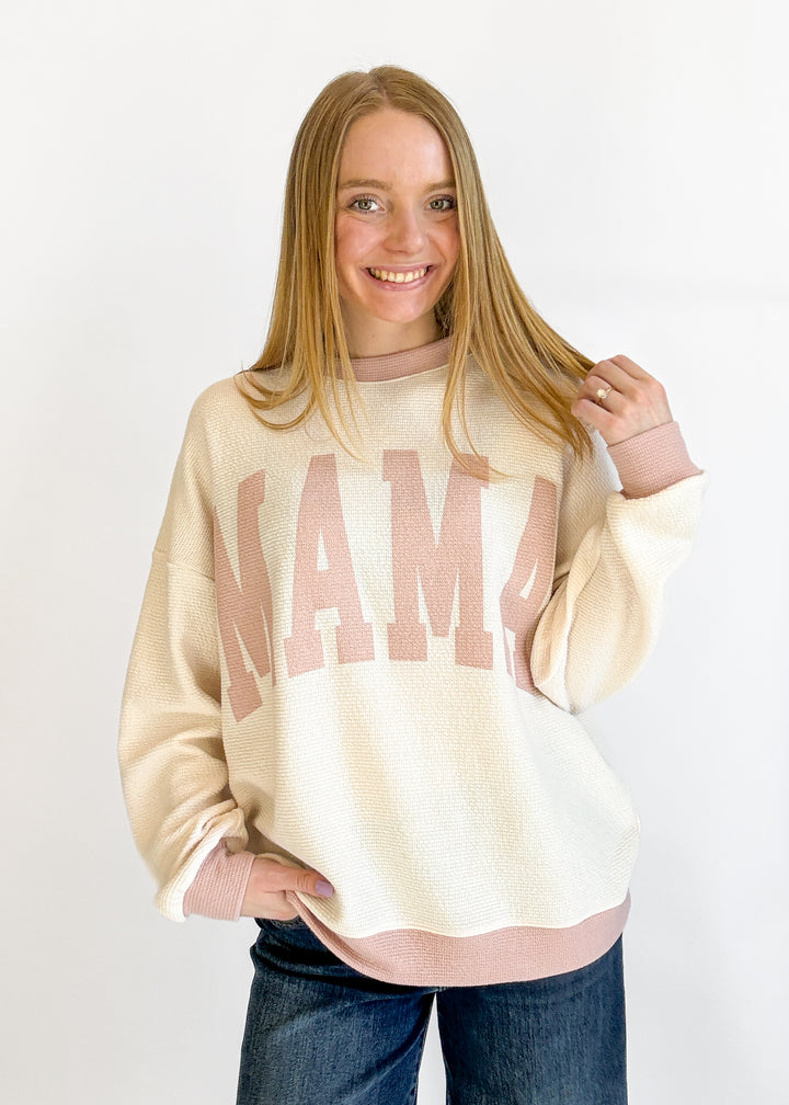 Woman wearing a cream sweatshirt with pink text on a white background