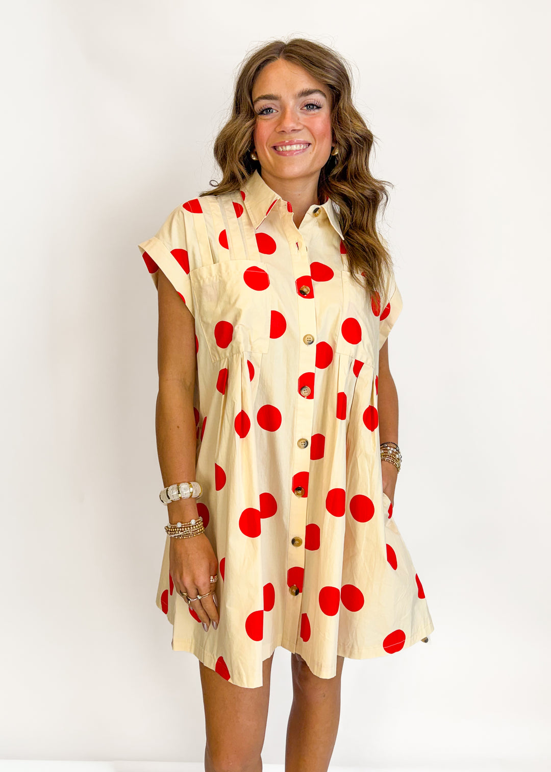 Woman wearing a cream dress with red polka dots against a white background