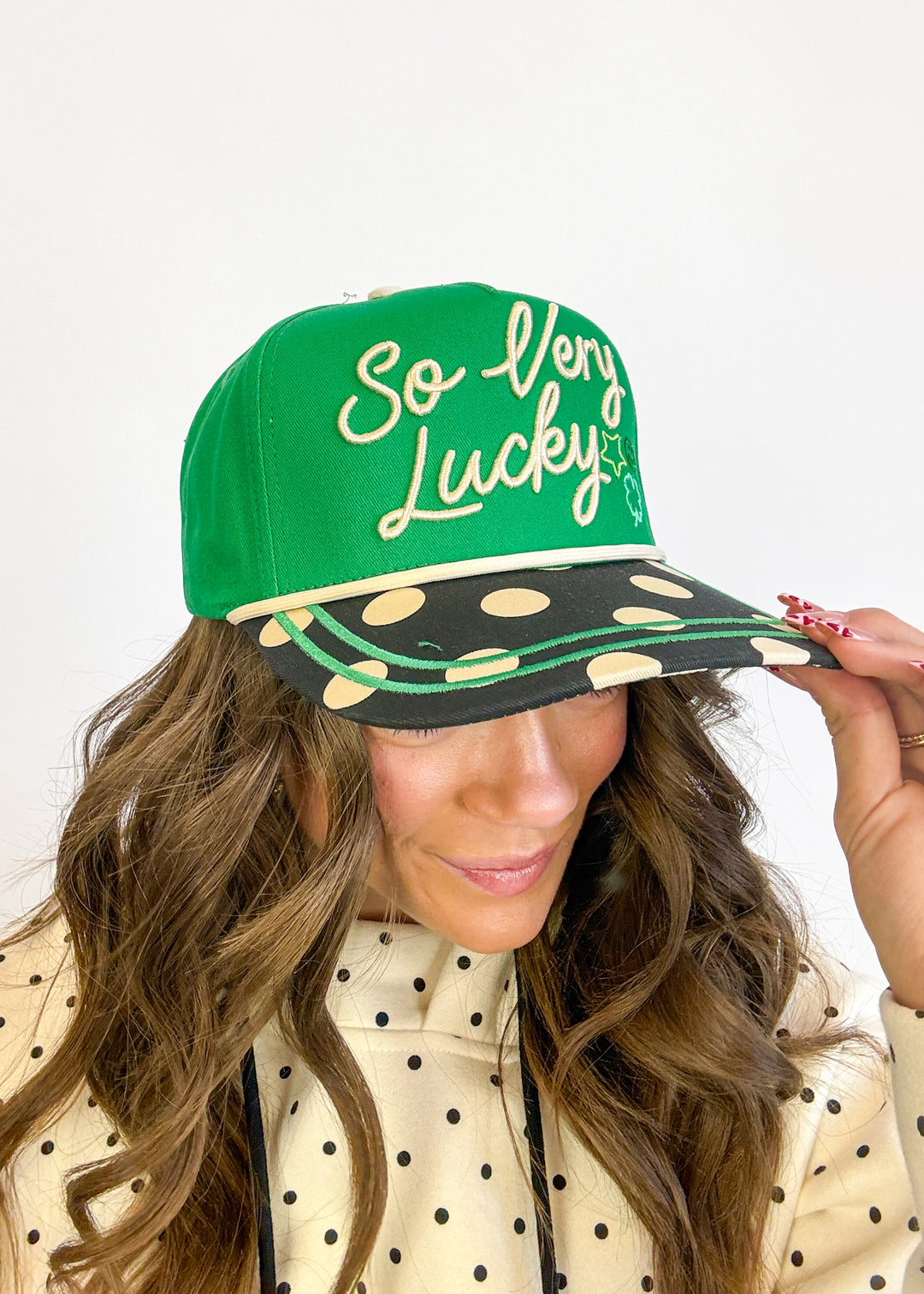 Person wearing a green and black cap with 'So Very Lucky' text on a white background