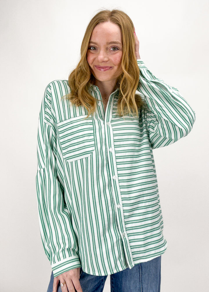 Woman wearing a green and white striped shirt against a white background