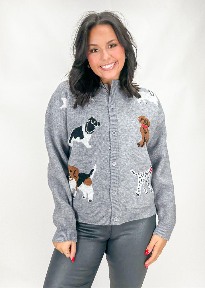 Woman wearing a gray cardigan with dog appliqués on a white background