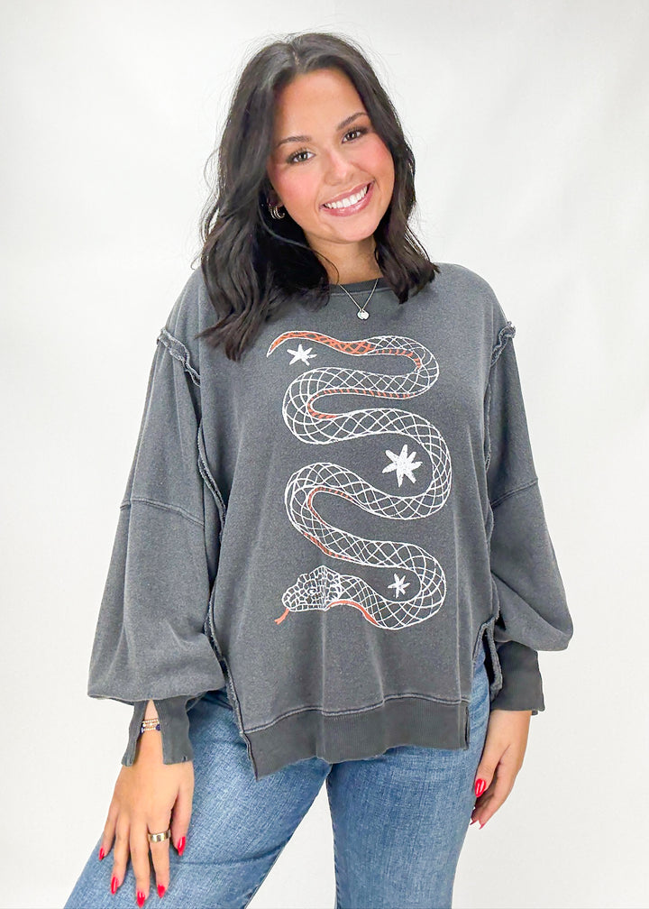 Woman wearing a gray sweatshirt with a snake design on a white background