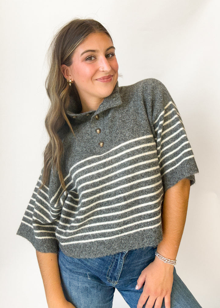 Woman wearing a grey short sleeve sweater with white stripes