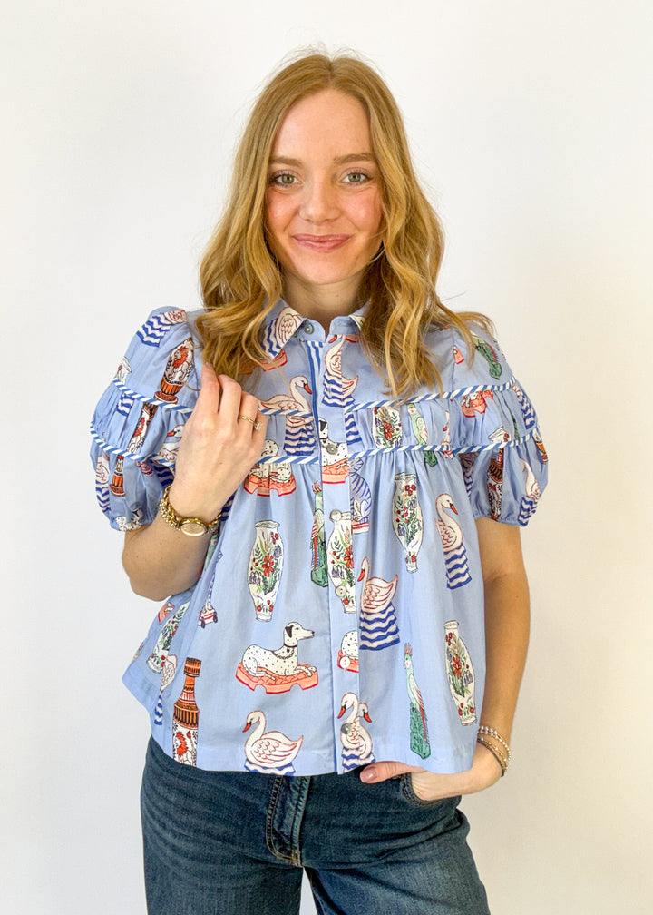 Woman wearing a blue patterned blouse with puff sleeves on a white background