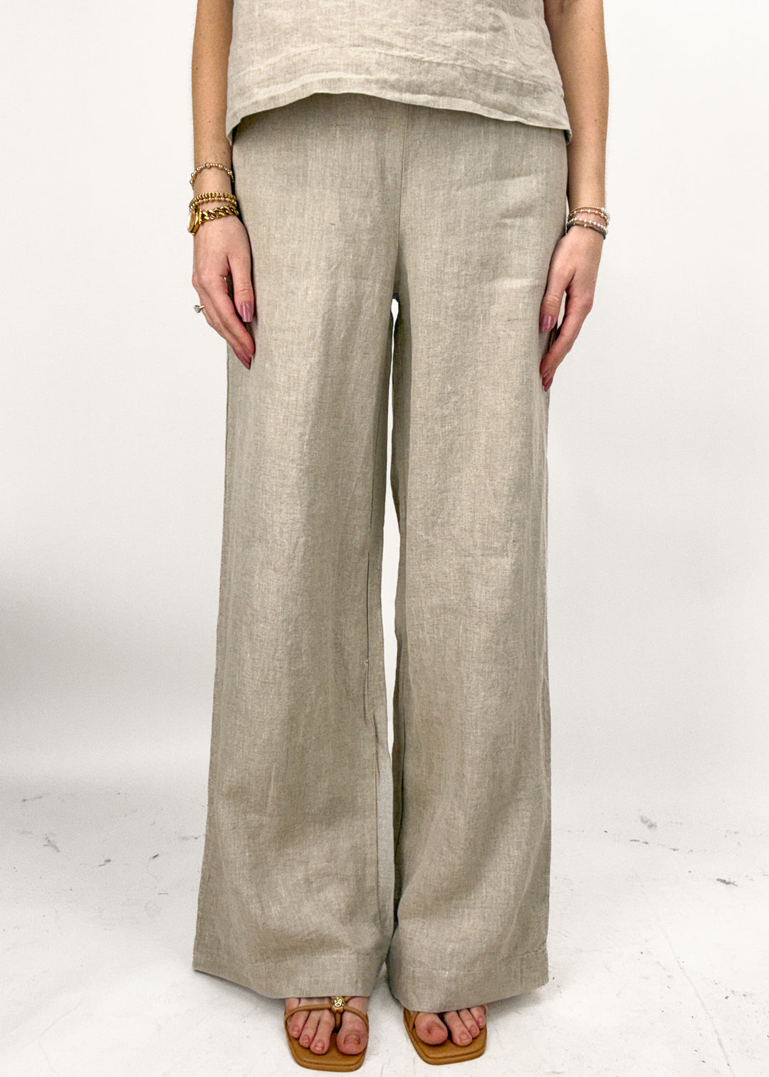 Person wearing beige wide-leg pants on a white background