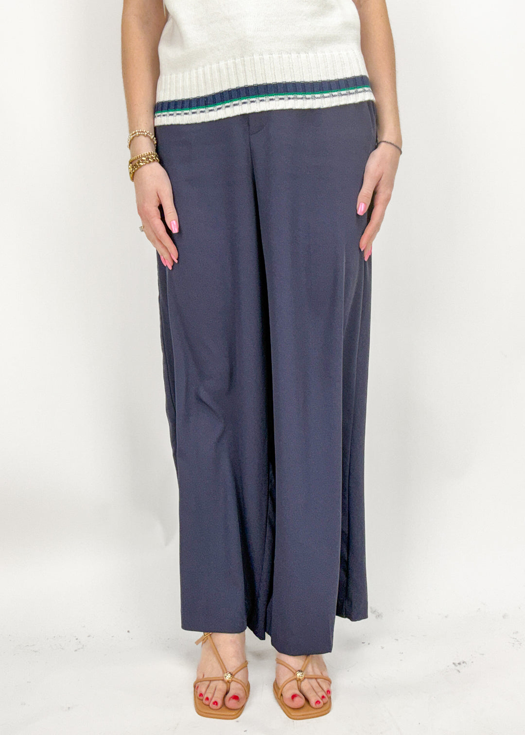Person wearing navy wide-leg pants with a white top on a white background