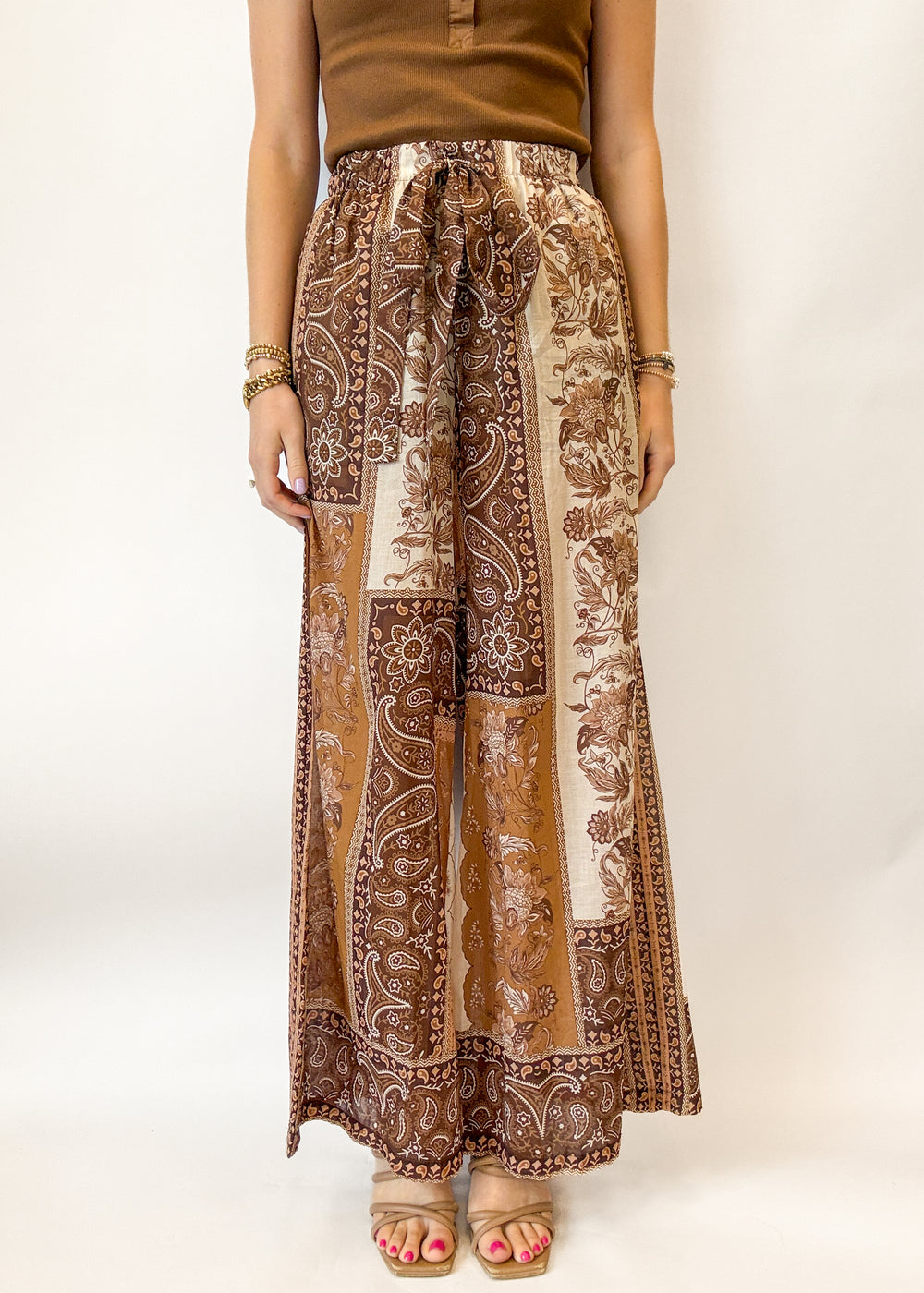 Person wearing brown patterned pants on a white background