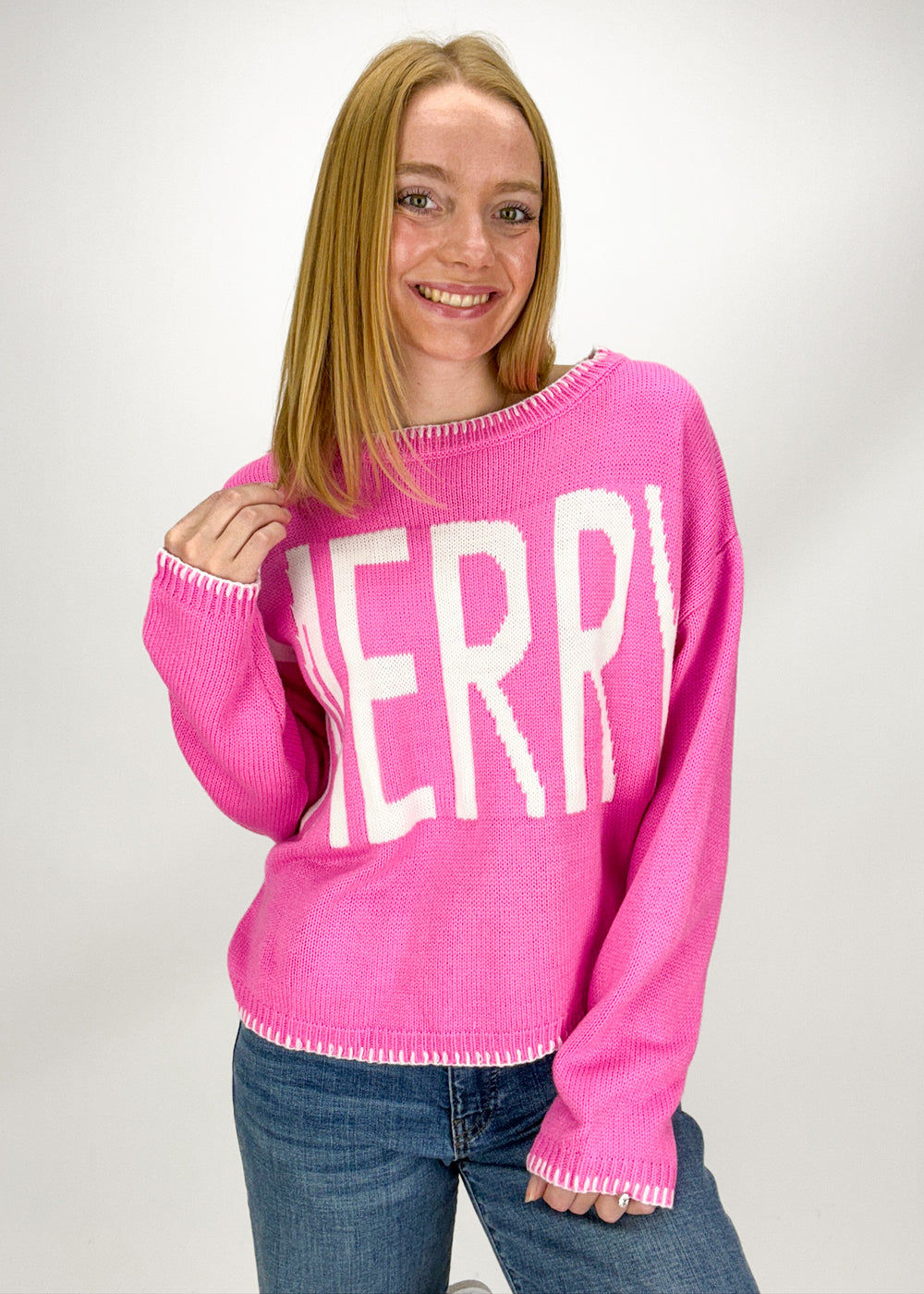 Person wearing a pink sweater with 'MERRY' text 