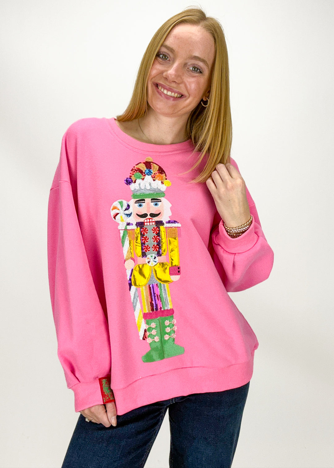 Person wearing a pink sweatshirt with a colorful nutcracker design 