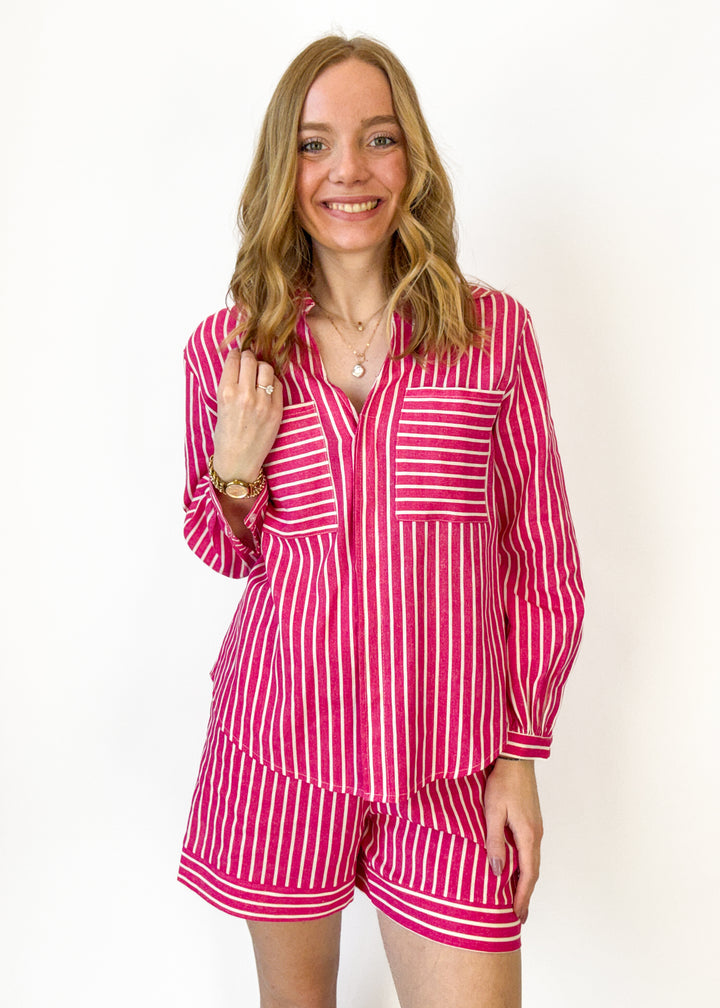 Woman wearing a pink and white striped pajama set against a plain background