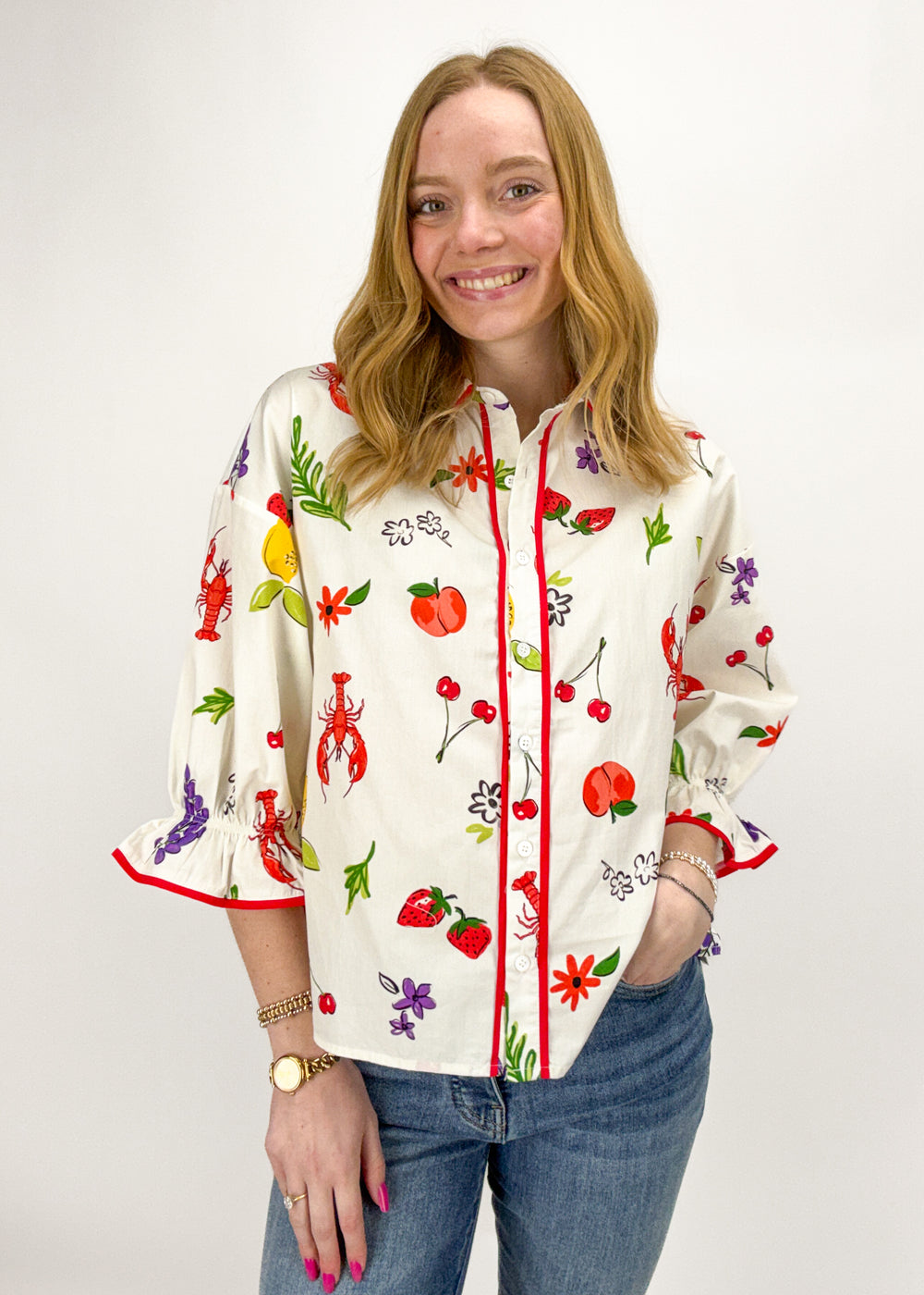 Woman wearing a colorful floral and fruit patterned shirt on a white background