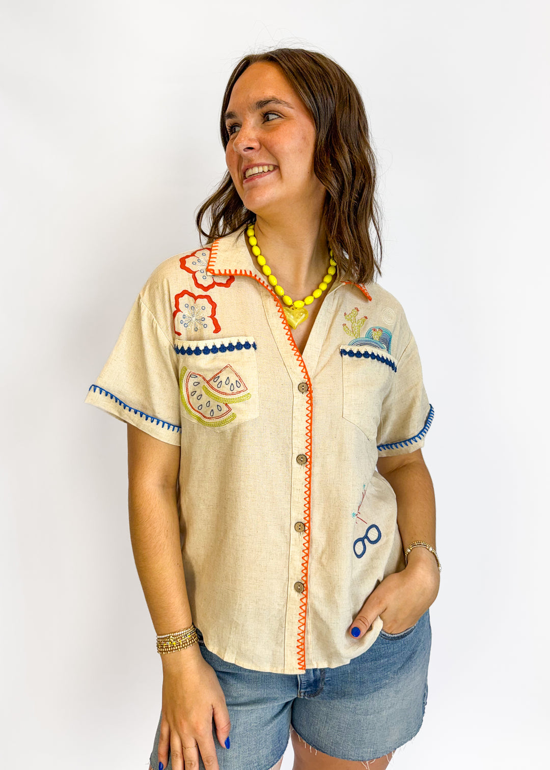 Woman wearing a decorative beige shirt with colorful patterns on a white background