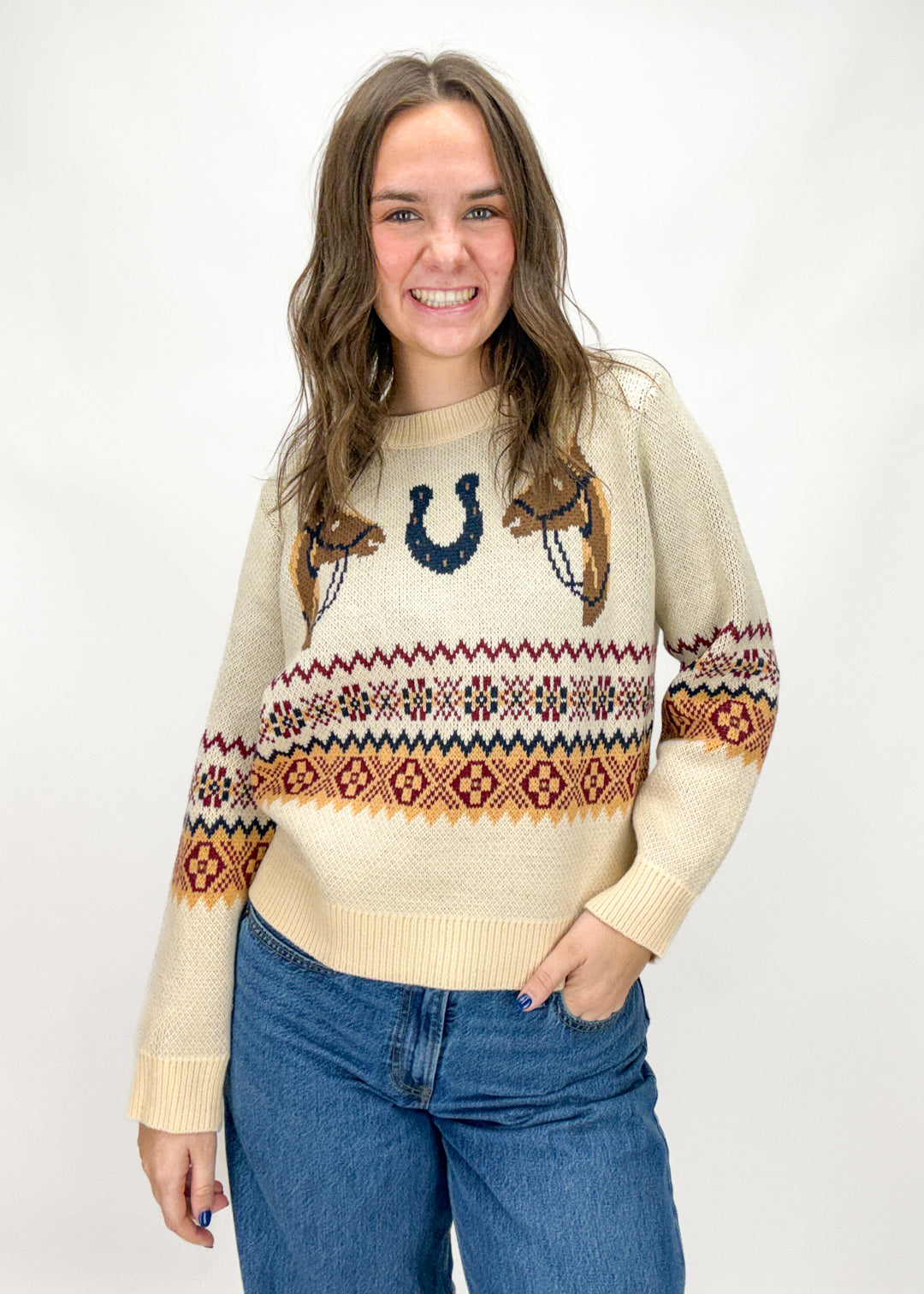 Woman wearing a patterned sweater with horse and horseshoe designs on a white background
