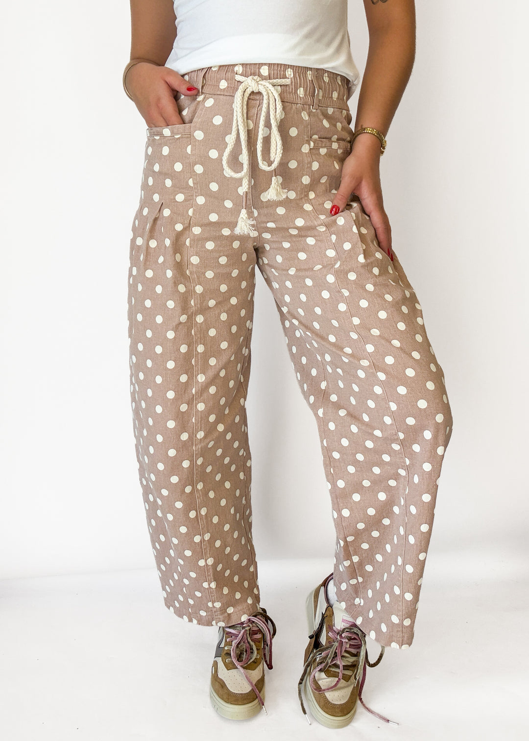 A person wearing loose, wide-leg cropped pants in a beige/tan base with white polka dots