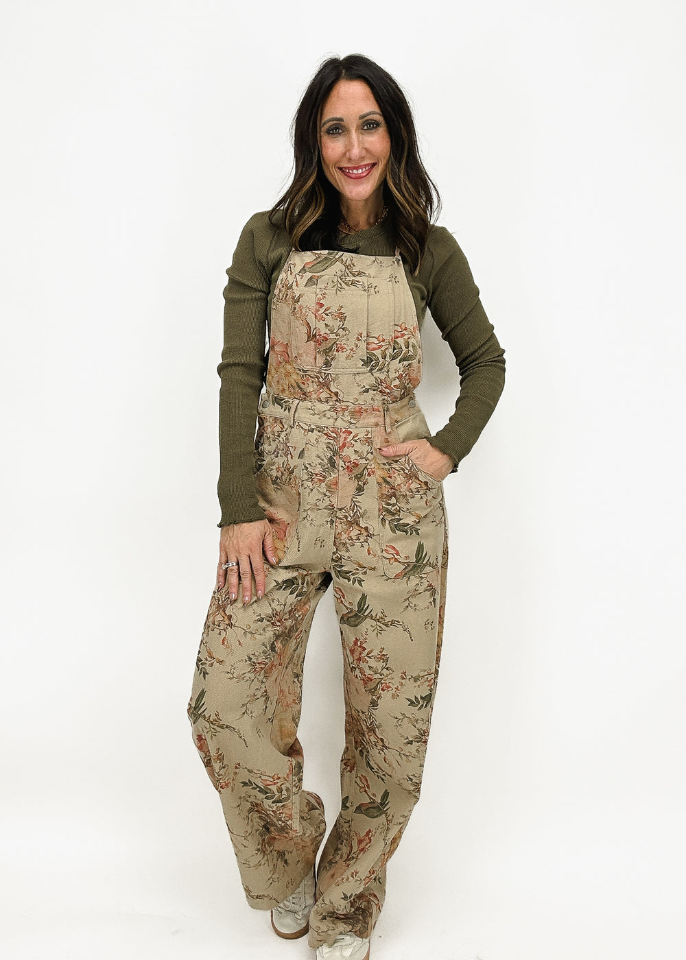 woman wearing taupe floral wide leg overalls over green long sleeve tee