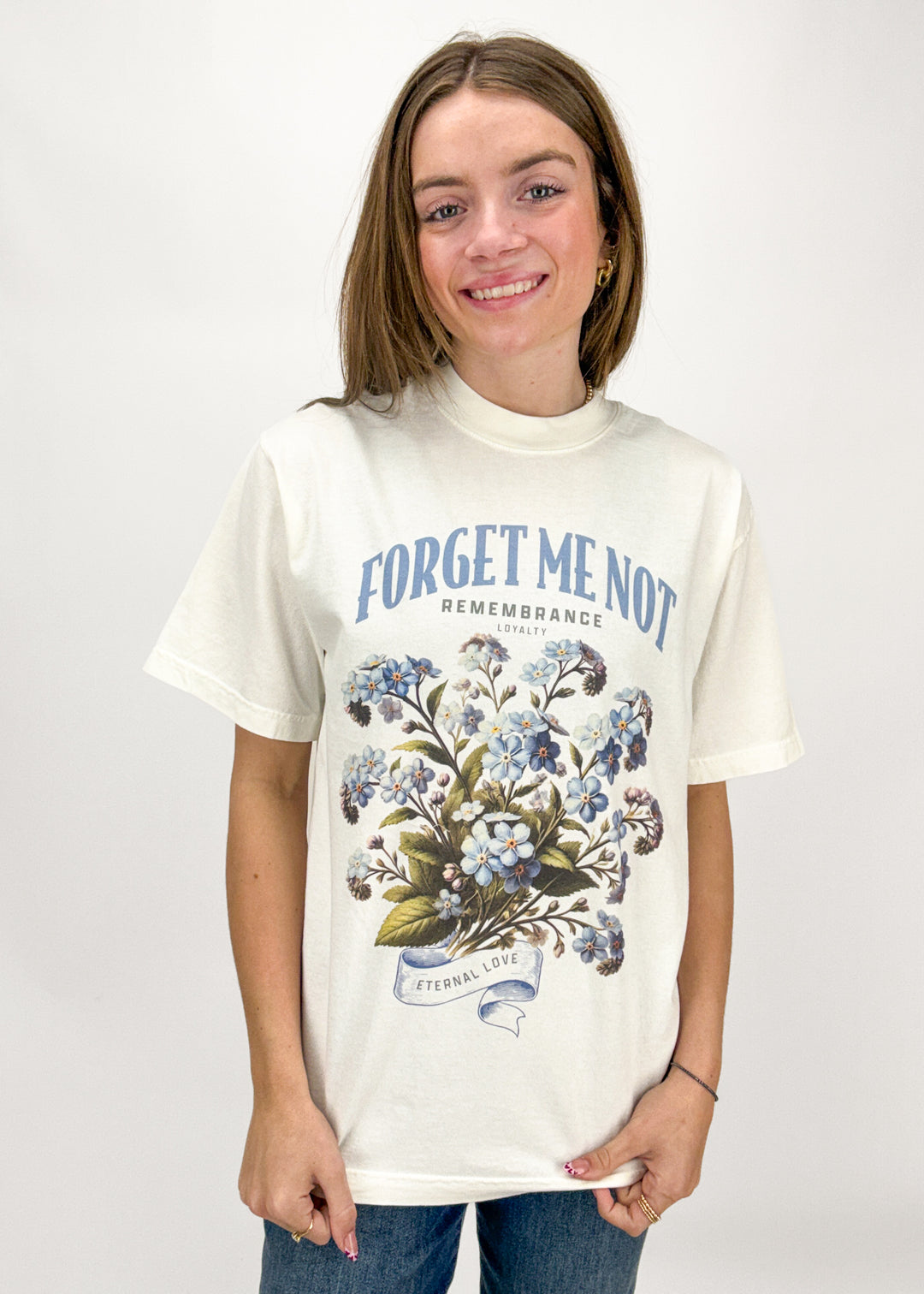 Person wearing a white t-shirt with floral design and text on a plain background