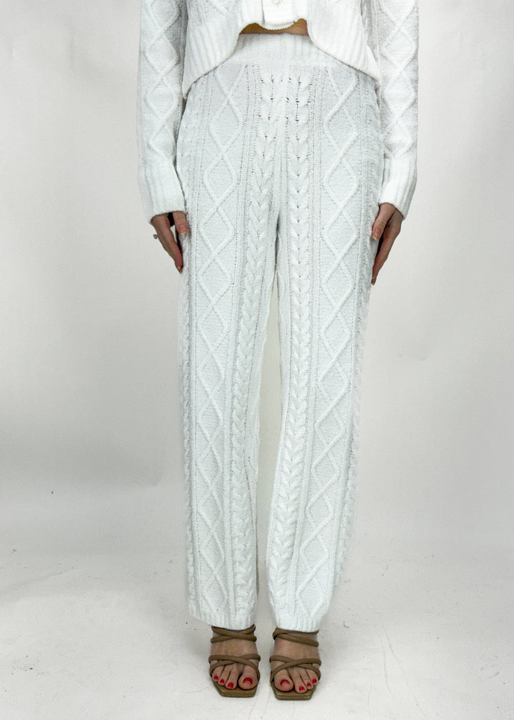 Person wearing white cable knit pants on a plain background