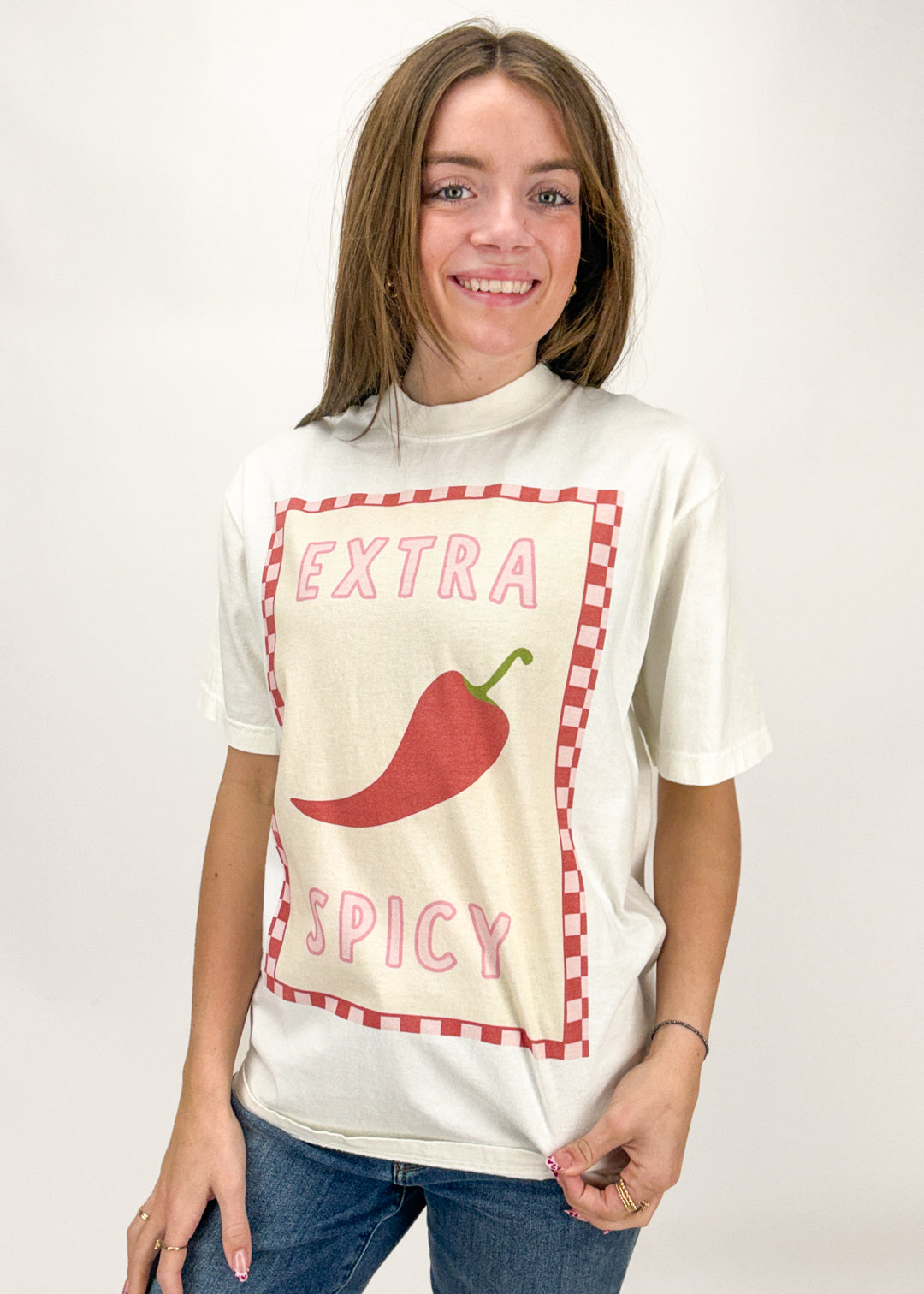 Person wearing a white t-shirt with a red chili pepper graphic and text on a plain background