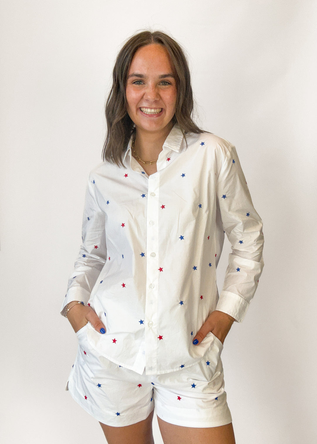 Woman wearing a white shirt with colorful star patterns and matching shorts on a plain background
