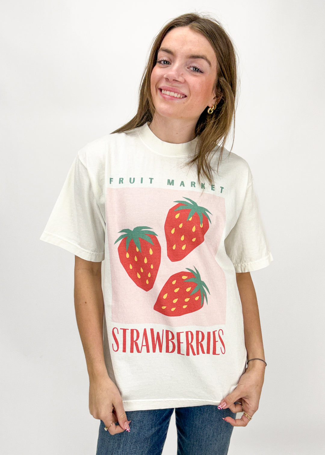 Person wearing a t-shirt with strawberry graphic and text on a white background