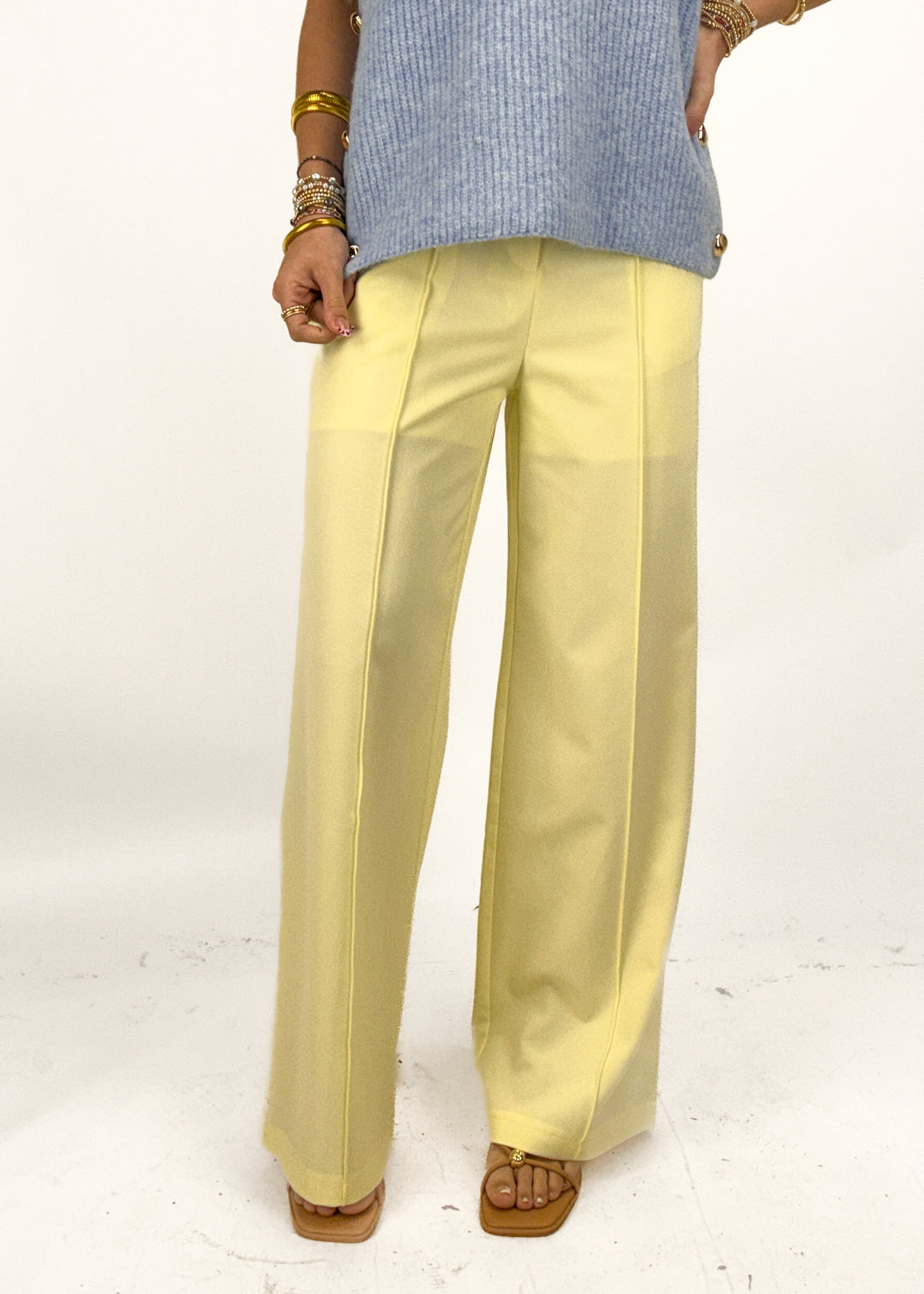 Person wearing light yellow pants and a blue sweater on a white background